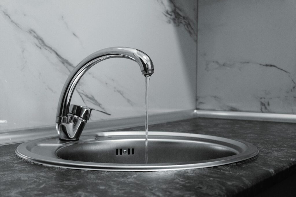 蛇口から流れる水。一人暮らしの水道代は1ヶ月約2,300円で、使用量の約4割がお風呂。会社は選べず地域差が大きいため使用量を減らす節約が中心と解説する本記事のイメージ。