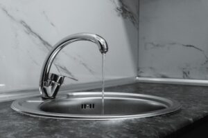 蛇口から流れる水。一人暮らしの水道代は1ヶ月約2,300円で、使用量の約4割がお風呂。会社は選べず地域差が大きいため使用量を減らす節約が中心と解説する本記事のイメージ。